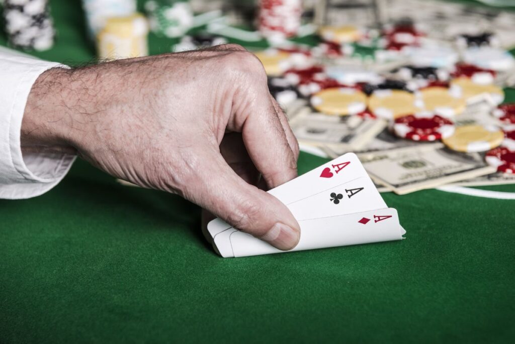 Main d’un joueur de poker dévoilant trois As combinaison gagnant