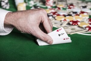 Main d’un joueur de poker dévoilant trois As combinaison gagnant