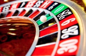 Gros plan sur une roue de roulette de casino avec la bille arrêtée sur la case verte du 0, entourée des cases rouges et noires numérotées