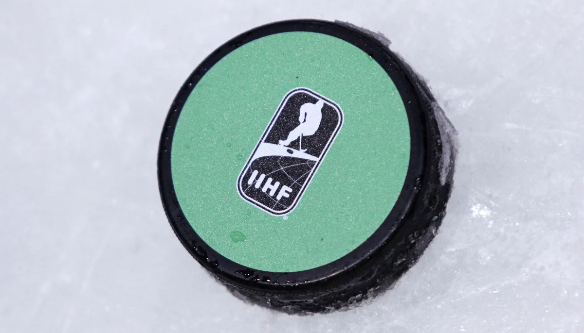 Ishockeypuck med IIHF logotyp liggande på isen under Junior VM turnering