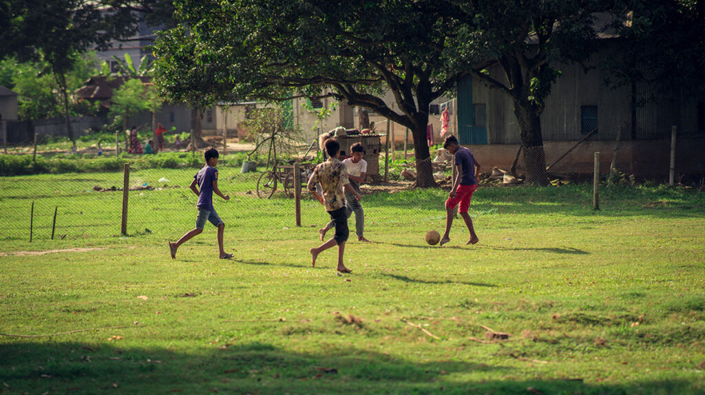Middle Eastern kids playing soccer together in a village.