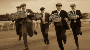 Sepia photo of men in vintage attire running a race, carrying baskets of poker chips.