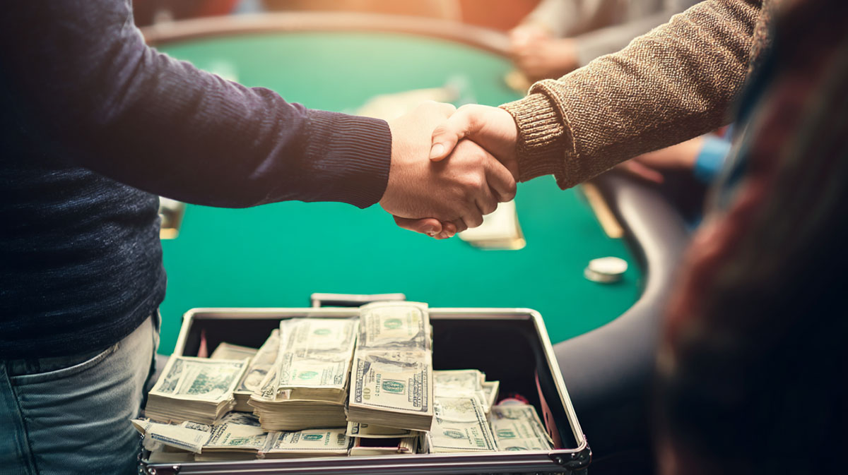 Two men shake hands at the poker table over a suitcase full of cash.