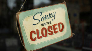 Vintage "Sorry, We're Closed" sign hanging in a shop window.