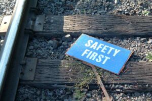 A sign reading 'safety first' laying on railroad tracks.