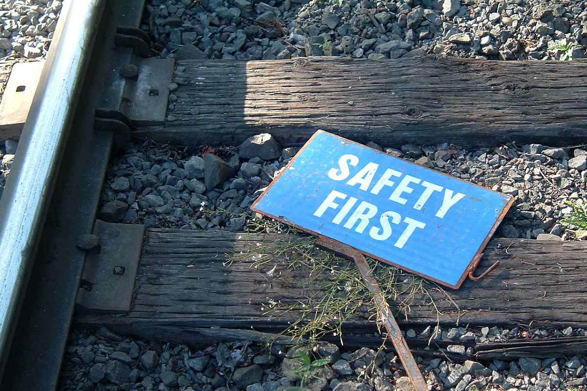 A sign reading 'safety first' laying on railroad tracks.