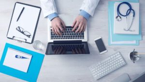 Doctor typing on laptop with medical equipment