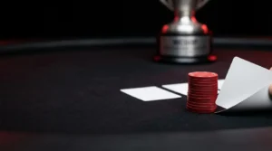 Close-up of a river card and red poker chips on a dark tournament table