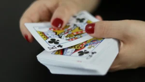 Hands with red nail polish holding and dealing a deck of playing cards